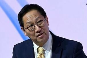 Santa Ono, an Asian man with black hair, wearing glasses and a dark suit with a yellow tie.