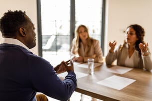 A photo of a job candidate meeting with two interviewers; they are engaged in an animated discussion.