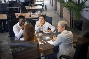 A group of four professionals sits around a conference table discussing ideas.