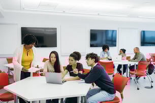 Teacher assisting university students in classroom