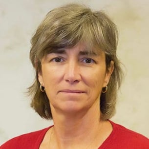 Irene Mulvey, a light-skinned woman with light brown hair, wearing small hoop earrings and a red top