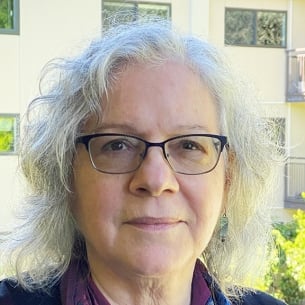 Nancy Harrowitz, a light-skinned woman with white hair, wearing glasses