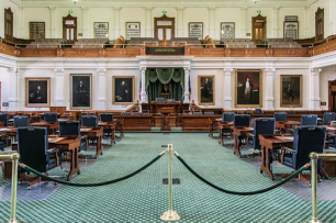 The Texas Senate chamber, with an aqua-blue rug and wooden desks and chair.