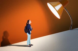 A student against an orange background with a spotlight shining down on them.