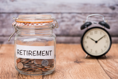 A jar of change, labeled with the word "Retirement," next to a clock.