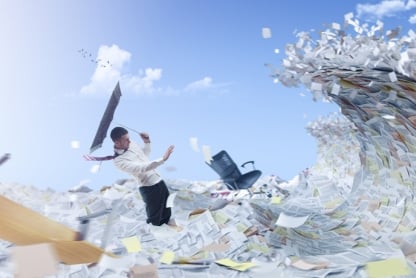 Man stands in a sea of paper holding an umbrella turned inside out as a huge wave of more paper approaches