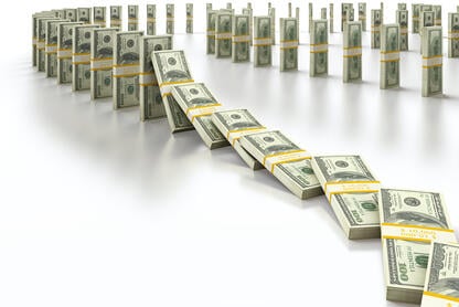 Stacks of $100 bills are lined up to mimic dominoes falling.