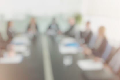 A blurry, out-of-focus picture of a group of trustees around a board table. 