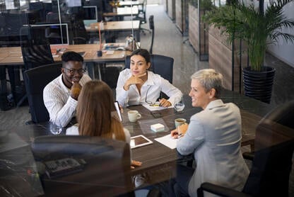 A group of four professionals sits around a conference table discussing ideas. 