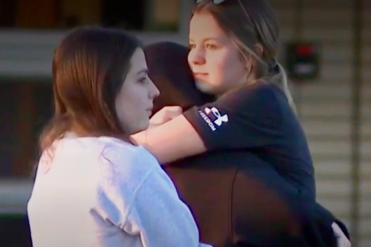 A female student comforts another with a hug