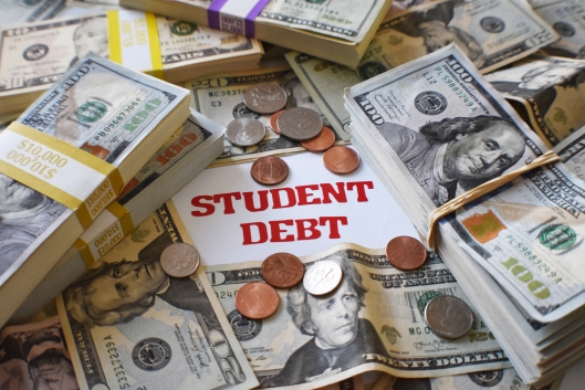 A pile of U.S. currency—bundles of $100 bills, scattered $20 bills and some coins—with the words "student debt" in the middle of the pile.