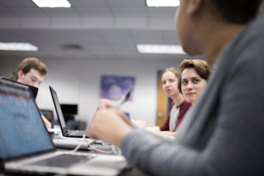 Several Tallahassee Community College students sit at a long table with laptops.