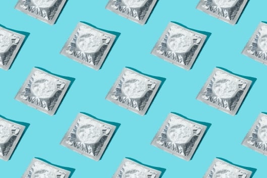 A pattern of silver condom wrappers on a blue background