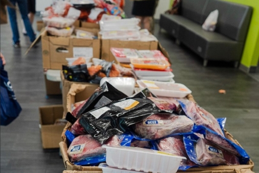 Pace University's mobile food pantry displays a variety of free food items, including plastic-wrapped cuts of meat.