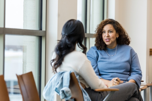 Two women seated talking, the older one giving advice to the other