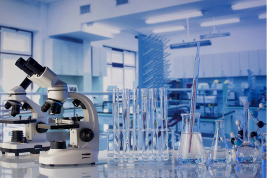 A scientific laboratory, featuring a microscope in the foreground and lots of glassware in the background.