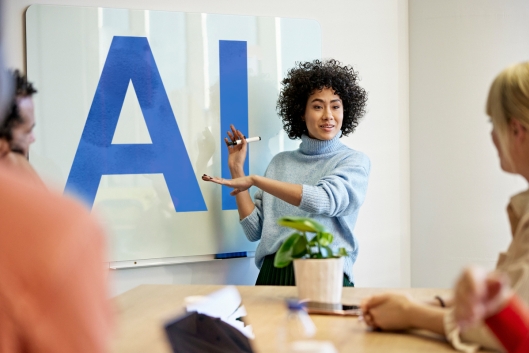 A woman points at large letters that spell out "AI"