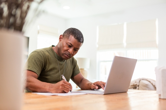 A mature veteran works at a computer on a table.