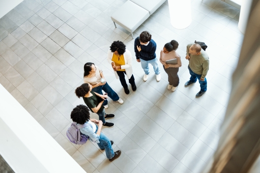 Group of diverse students gathered around a professor and talking