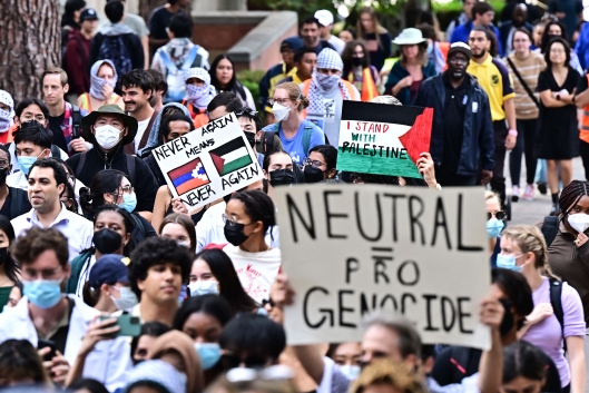 Pro-Palestinian students protest at UCLA. One holds a sign that reads "neutral = pro genocide."