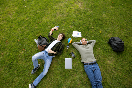 Two male university students hanging out on a campus's lawn