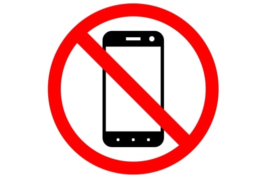 A sign prohibiting smartphone usage, featuring a black-and-white drawing of a smartphone inside a red circle with a diagonal slash through it.