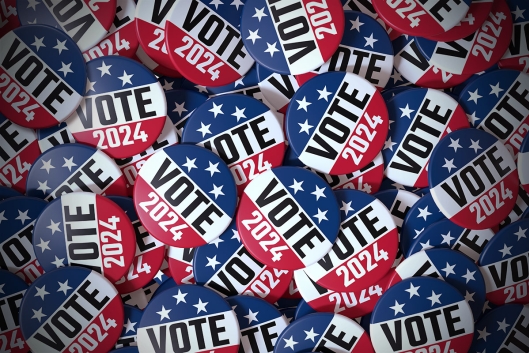Red, white and blue buttons saying Vote 2024 lie in a pile