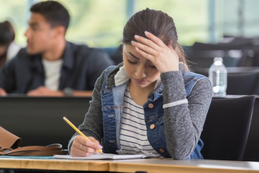 A stressed-out student works at her desk.