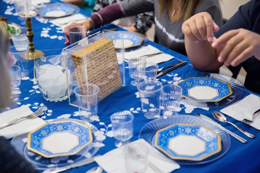 A table set for Passover dinner with blue plates and tablecloths and matzah in the center.
