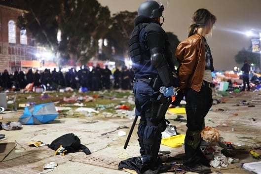A photograph of an officer in riot gear arresting a protester in the pro-Palestinian campus encampment at the University of California, Los Angeles..