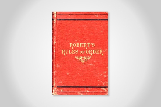 An aged copy of the original Robert's Rules of Order. The cover is red with gold writing.