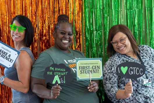 Students pose in a photo booth, holding signs that say "First-gen student," "I make a difference" and "I heart GTCC."