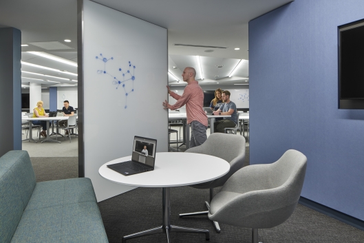 Professor moves a whiteboard into a secluded space from which you can see a larger classroom
