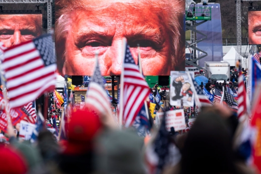 Large images of former president Trump's face on video screens loomed over a crowd of his supporters, many bearing American flags, as they gathered at the White House on Jan. 6, 2021.