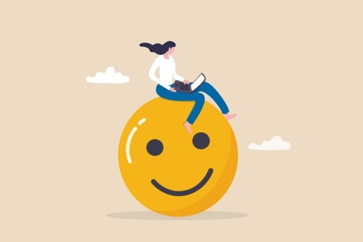 An illustration of a woman with an open laptop sitting atop a large yellow smiley face.