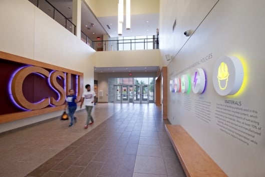 Two students walk down a hallway that reads "CSU" in large letters.