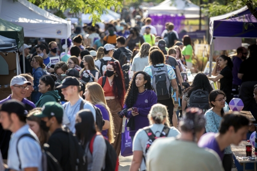 A crowd mills on a campus between vendor tents