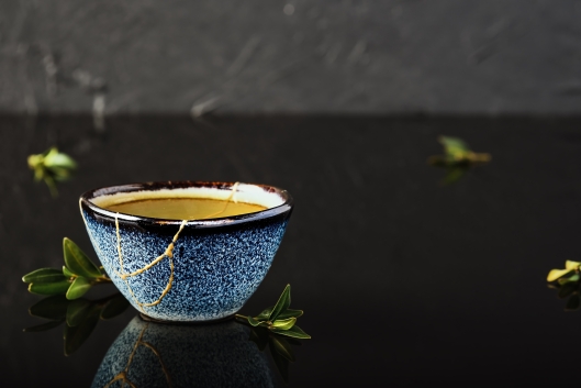 A blue ceramic bowl with its cracks mended with gold in the kintsugi style