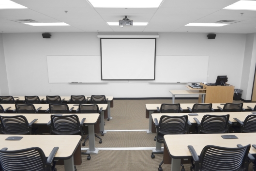 An empty college classroom, with a blank whiteboard at the front.