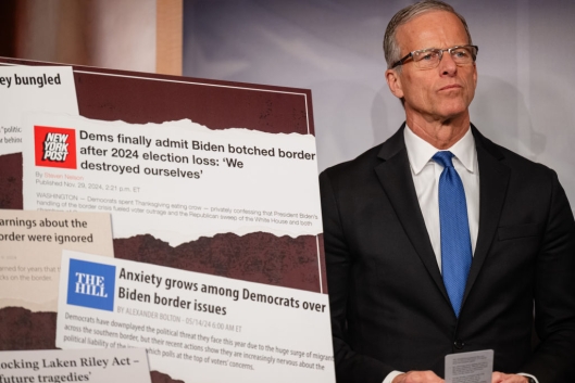 John Thune stands next to a poster of screenshots about the Democrats and border security
