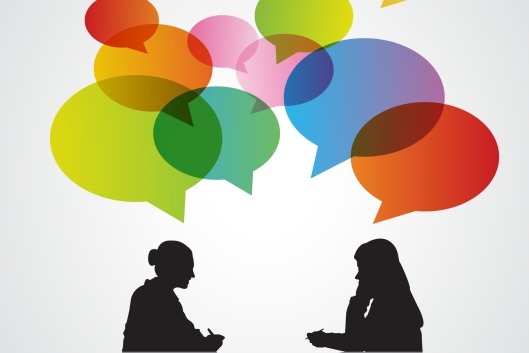 An illustration of two women, in silhouette, talking, with multicolored speech bubbles above their heads.