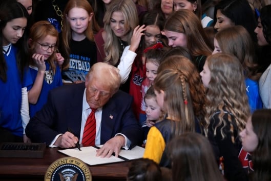 Trump signs EO surrounded by a crowd of young girls