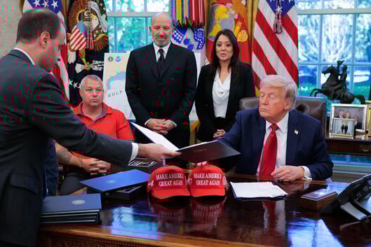 White House staff secretary Will Scharf hands U.S. President Donald Trump an executive order to sign in the Oval Office.
