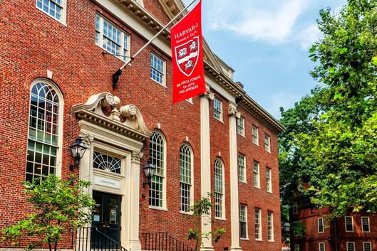 A flag with the Harvard University logo hangs above the entrance of Harvard's Lehman Hall. 