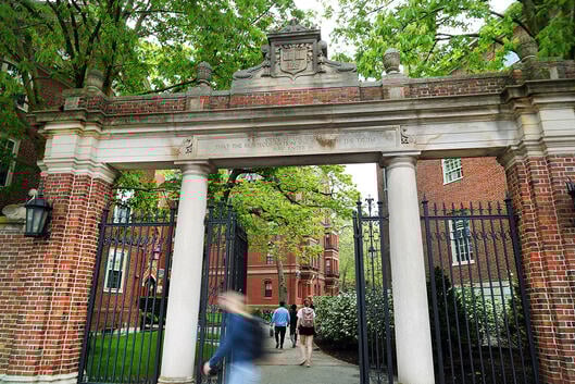 People enter Harvard Yard through a gate.