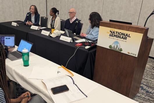 Four panelists sit at a table next to a lectern with the Education Writers Association logo on it.