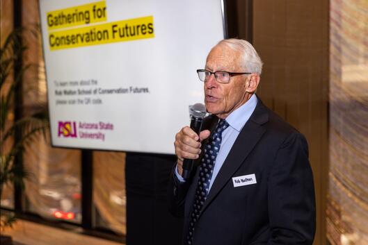 Rob Walton, a light-skinned man with white hair and glasses, speaks into a microphone.