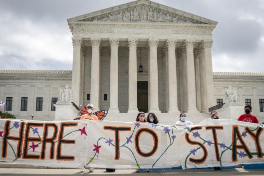 A group of students hold a sign reading "here to stay" in front of the U.S. Supreme Court in Washington, D.C.