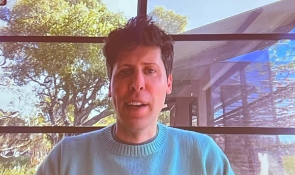 Photo of a man, OpenAI co-founder Sam Altman, in a green sweater speaking 