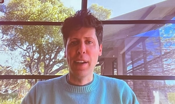 Photo of a man, OpenAI co-founder Sam Altman, in a green sweater speaking